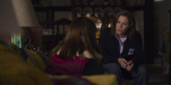 Movie still from “Mixtape” (2021), directed by Valerie Weiss – A woman sitting next to another woman in a room; Medium shot, Over the shoulder angle