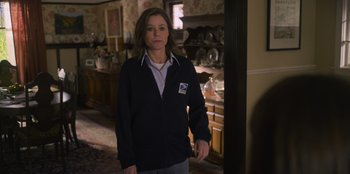 Movie still from “Mixtape” (2021), directed by Valerie Weiss – A person standing in a room with a lot of furniture in the background; Medium shot, Low angle