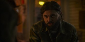 Movie still from “Mixtape” (2021), directed by Valerie Weiss – A man with long hair and a beard stares at the camera; Close Up shot, Over the shoulder angle