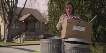 Movie still from “Mixtape” (2021), directed by Valerie Weiss – A woman holding a cardboard box next to a trash can; Medium shot, Low angle
