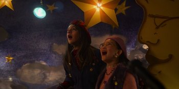 Movie still from “Mixtape” (2021), directed by Valerie Weiss – Two young girls singing in front of a star; Medium shot, Low angle