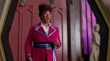 Movie still from “Monster High 2” (2023), directed by Todd Holland – A woman in a pink coat and blue belt; Medium shot, Low angle