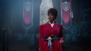 Movie still from “Monster High 2” (2023), directed by Todd Holland – A woman in a red dress standing in front of a stage; Medium shot, Over the shoulder angle