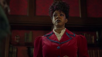 Movie still from “Monster High 2” (2023), directed by Todd Holland – A woman in a red jacket looking up at the ceiling; Medium shot, Low angle