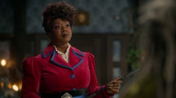 Movie still from “Monster High 2” (2023), directed by Todd Holland – A woman in a red jacket holding a wand; Medium shot, Over the shoulder angle