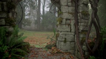 Movie still from “Monster High 2” (2023), directed by Todd Holland – A stone wall in the middle of a foggy forest; Extreme Wide shot, High angle