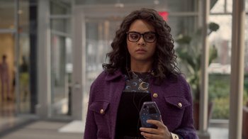 Movie still from “Monster High 2” (2023), directed by Todd Holland – A woman in a purple jacket holding a cell phone; Medium shot, Over the shoulder angle