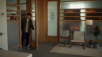 Movie still from “Monster High 2” (2023), directed by Todd Holland – A man standing in front of an open door in a room; Wide shot, Over the shoulder angle