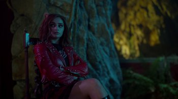 Movie still from “Monster High 2” (2023), directed by Todd Holland – A woman in a red leather jacket sitting in front of a tree; Medium shot, Over the shoulder angle