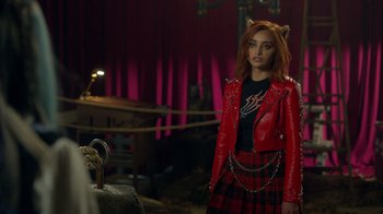 Movie still from “Monster High 2” (2023), directed by Todd Holland – A woman in a red leather jacket standing in a room; Medium shot, Over the shoulder angle