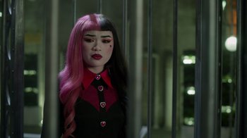 Movie still from “Monster High 2” (2023), directed by Todd Holland – A woman with pink and black hair in front of a jail cell; Close Up shot, Over the shoulder angle