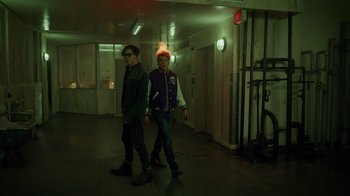 Movie still from “Monster High 2” (2023), directed by Todd Holland – Two people walking in a building at night; Medium shot, Over the shoulder angle