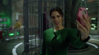 Movie still from “Monster High 2” (2023), directed by Todd Holland – A woman in a green dress smiling for the camera; Medium shot, Low angle