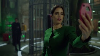 Movie still from “Monster High 2” (2023), directed by Todd Holland – A woman in a green dress standing in front of a metal cage; Medium shot, Low angle