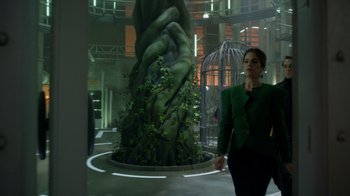 Movie still from “Monster High 2” (2023), directed by Todd Holland – A woman in a green suit walking in front of a statue; Wide shot, Low angle