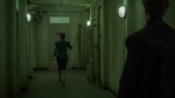 Movie still from “Monster High 2” (2023), directed by Todd Holland – A woman walking down a hallway in a building; Wide shot, Over the shoulder angle