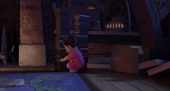 Movie still from “Monsters, Inc.” (2001), directed by Pete Docter – A little girl sitting on the floor next to a stack of books; Medium shot, Over the shoulder angle