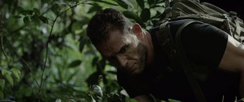 Movie still from “Monsters of Man” (2020), directed by Mark Toia – A person with a beard in the woods; Close Up shot, Low angle