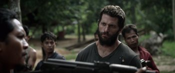 Movie still from “Monsters of Man” (2020), directed by Mark Toia – A man with a beard is standing next to another man with a gun; Close Up shot, Over the shoulder angle