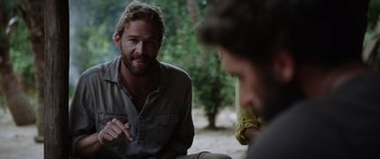 Movie still from “Monsters of Man” (2020), directed by Mark Toia – A man sitting on the ground talking to another man; Medium shot, Over the shoulder angle