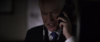 Movie still from “Monsters of Man” (2020), directed by Mark Toia – An older man in a suit and tie talking on a cell phone; Close Up shot, Low angle