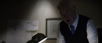 Movie still from “Monsters of Man” (2020), directed by Mark Toia – An older man in a suit and tie looking at a lamp; Close Up shot, Over the shoulder angle