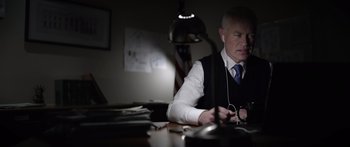 Movie still from “Monsters of Man” (2020), directed by Mark Toia – A man sitting at a desk listening to headphones; Close Up shot, Low angle