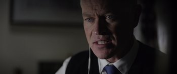 Movie still from “Monsters of Man” (2020), directed by Mark Toia – An older man wearing a suit and tie; Close Up shot, Over the shoulder angle