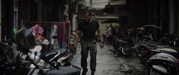 Movie still from “Monsters of Man” (2020), directed by Mark Toia – A man walking down a street near parked motorcycles; Medium shot, Low angle