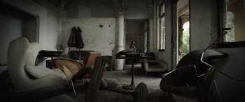 Movie still from “Monsters of Man” (2020), directed by Mark Toia – An abandoned room with a woman sitting on the floor; Wide shot, Low angle