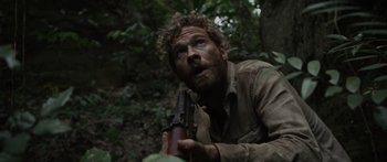 Movie still from “Monsters of Man” (2020), directed by Mark Toia – A man holding a gun in the woods looking surprised; Close Up shot, Low angle