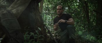 Movie still from “Monsters of Man” (2020), directed by Mark Toia – A man in the woods holding a pair of wrenches; Medium shot, Over the shoulder angle