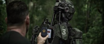Movie still from “Monsters of Man” (2020), directed by Mark Toia – A person holding a remote control in front of a robot; Close Up shot, Over the shoulder angle