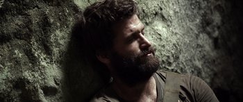 Movie still from “Monsters of Man” (2020), directed by Mark Toia – A man with a beard is leaning against a wall; Close Up shot, Low angle