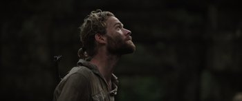 Movie still from “Monsters of Man” (2020), directed by Mark Toia – A man with a beard is looking up at the sky; Close Up shot, Low angle