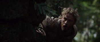 Movie still from “Monsters of Man” (2020), directed by Mark Toia – A man with a beard is holding a knife in a tree; Close Up shot, Over the shoulder angle