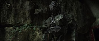 Movie still from “Monsters of Man” (2020), directed by Mark Toia – A robot standing in front of a cave; Wide shot, Low angle
