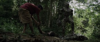 Movie still from “Monsters of Man” (2020), directed by Mark Toia – A man is standing over a dead body in the woods; Wide shot, Low angle