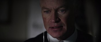 Movie still from “Monsters of Man” (2020), directed by Mark Toia – A person wearing a suit and tie; Close Up shot, Over the shoulder angle