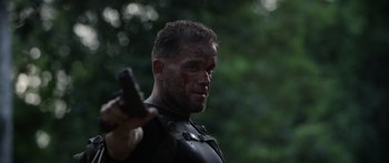 Movie still from “Monsters of Man” (2020), directed by Mark Toia – A person holding a gun in a forest; Close Up shot, Over the shoulder angle