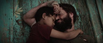 Movie still from “Monsters of Man” (2020), directed by Mark Toia – A man and a boy are laying on the ground; Close Up shot, Overhead angle