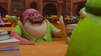 Movie still from “Monsters University” (2013), directed by Dan Scanlon – A cartoon character sitting at a table in front of a book case; Medium shot, Over the shoulder angle
