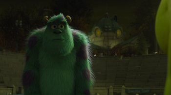 Movie still from “Monsters University” (2013), directed by Dan Scanlon – A green furry monster standing in front of a building; Extreme Wide shot, Low angle