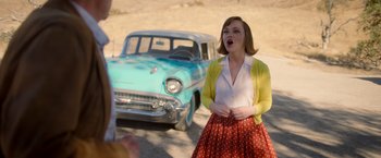 Movie still from “Monstrous” (2022), directed by Chris Sivertson – A woman in front of an old blue car; Medium shot, Over the shoulder angle