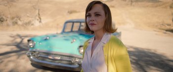Movie still from “Monstrous” (2022), directed by Chris Sivertson – A woman standing in front of an old car; Medium shot, Over the shoulder angle
