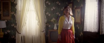 Movie still from “Monstrous” (2022), directed by Chris Sivertson – A woman standing in front of a window in a room; Medium shot, Over the shoulder angle