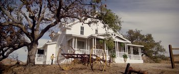 Movie still from “Monstrous” (2022), directed by Chris Sivertson – An old farm tractor sitting in front of a white house; Extreme Wide shot, Low angle