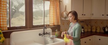Movie still from “Monstrous” (2022), directed by Chris Sivertson – A woman in a kitchen washing a banana peel; Medium shot, Low angle