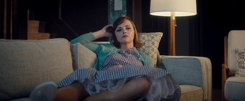Movie still from “Monstrous” (2022), directed by Chris Sivertson – A woman sitting on top of a couch in a living room; Medium shot, Low angle
