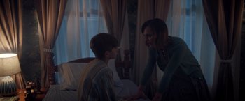 Movie still from “Monstrous” (2022), directed by Chris Sivertson – A woman and a boy are talking in a room; Medium shot, Over the shoulder angle